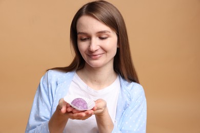 Photo of Woman with tasty mochi on light brown background