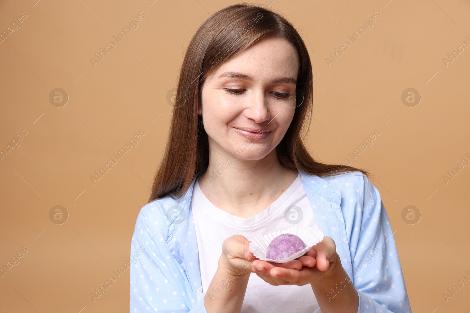 Photo of Woman with tasty mochi on light brown background