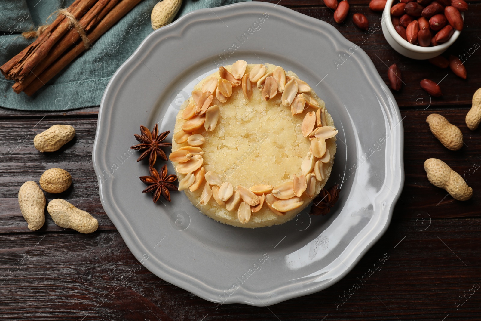 Photo of Delicious semolina halva with almond flakes and spices on wooden table, flat lay