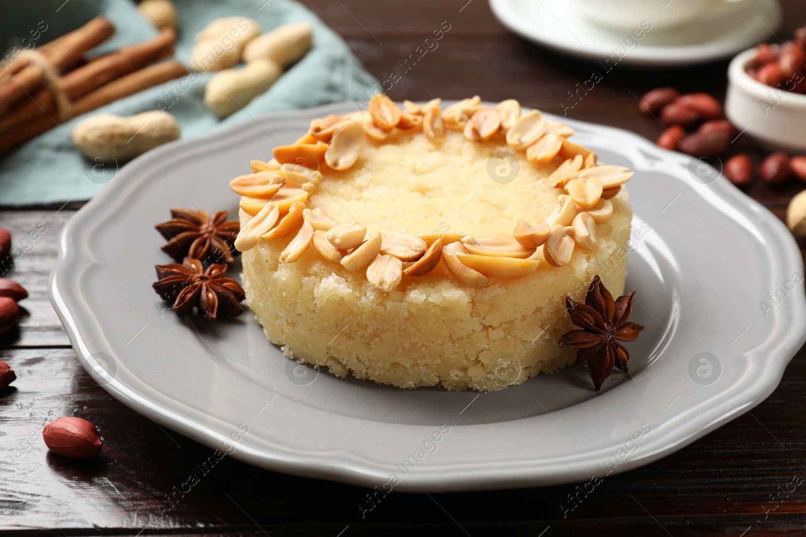 Photo of Delicious semolina halva with almond flakes and spices on wooden table, closeup