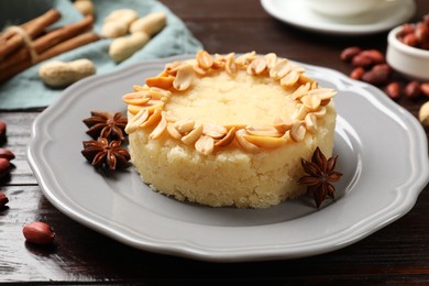 Photo of Delicious semolina halva with almond flakes and spices on wooden table, closeup