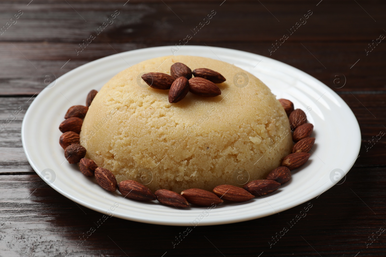 Photo of Delicious semolina halva with almonds on wooden table