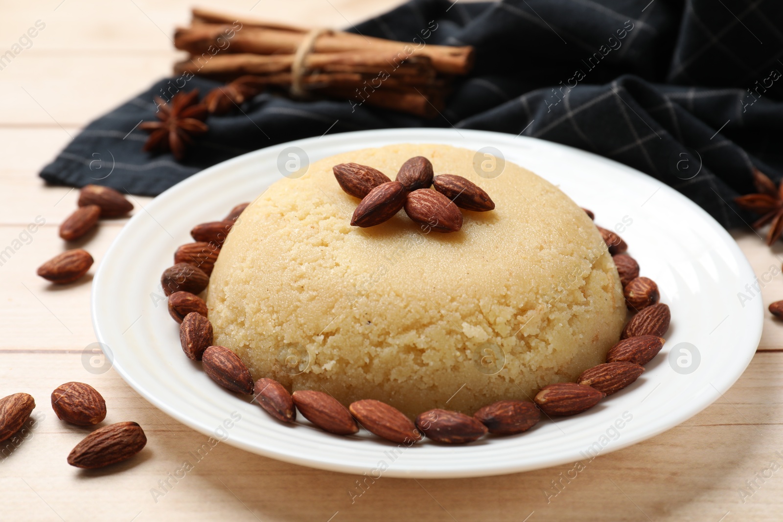 Photo of Delicious semolina halva with almonds on white wooden table, closeup