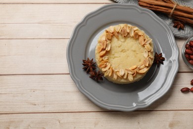 Photo of Delicious semolina halva with almond flakes and spices on white wooden table, flat lay. Space for text