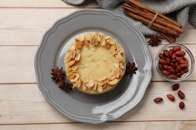 Photo of Delicious semolina halva with almond flakes and spices on white wooden table, flat lay