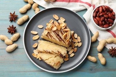 Photo of Delicious sweet semolina halva with peanuts and spices on blue wooden table, flat lay