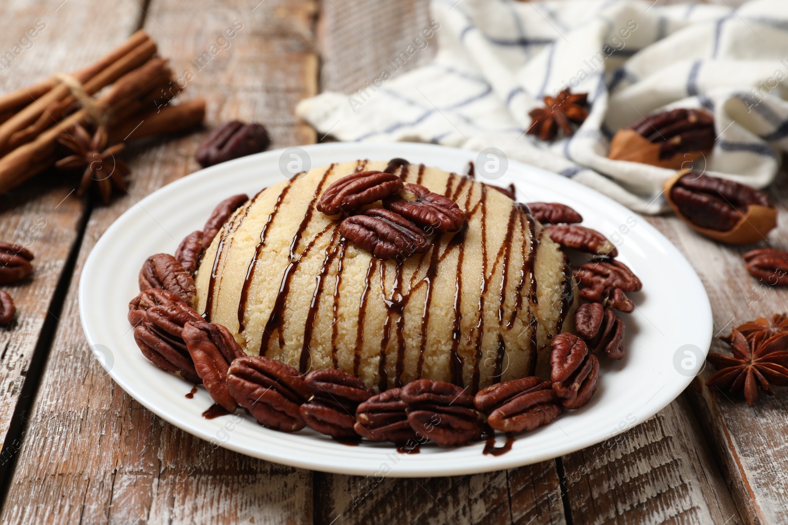 Photo of Delicious sweet semolina halva with pecans and spices on wooden table, closeup