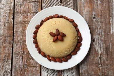 Photo of Delicious sweet semolina halva with almond on wooden table, top view