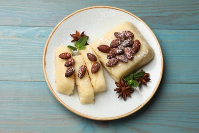 Photo of Delicious sweet semolina halva with almonds, spices and mint on light blue wooden table, top view