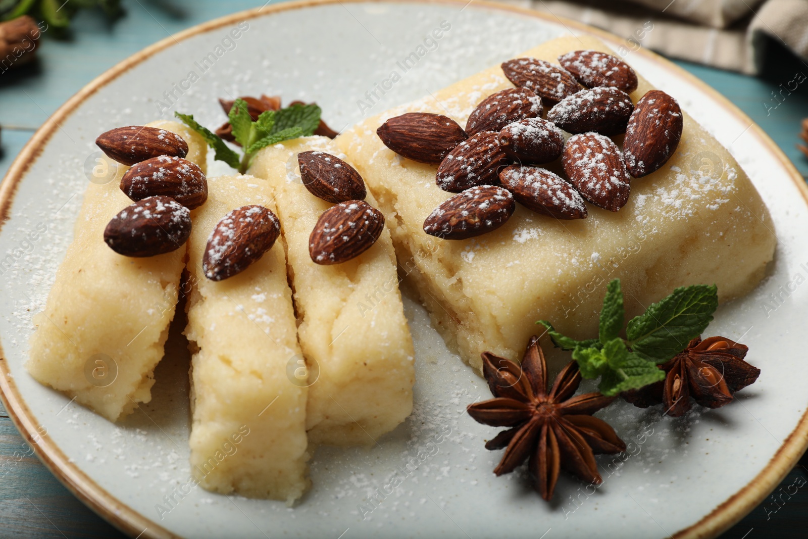 Photo of Delicious sweet semolina halva with almonds, spices and mint on table, closeup