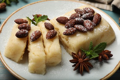 Photo of Delicious sweet semolina halva with almonds, spices and mint on table, closeup