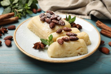 Photo of Delicious sweet semolina halva with almonds, spices and mint on light blue wooden table, closeup