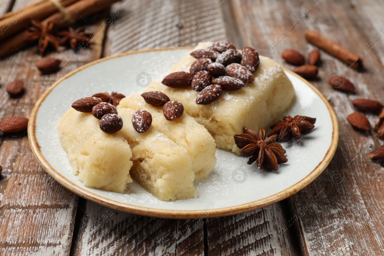 Photo of Delicious sweet semolina halva with almonds and spices on wooden table, closeup