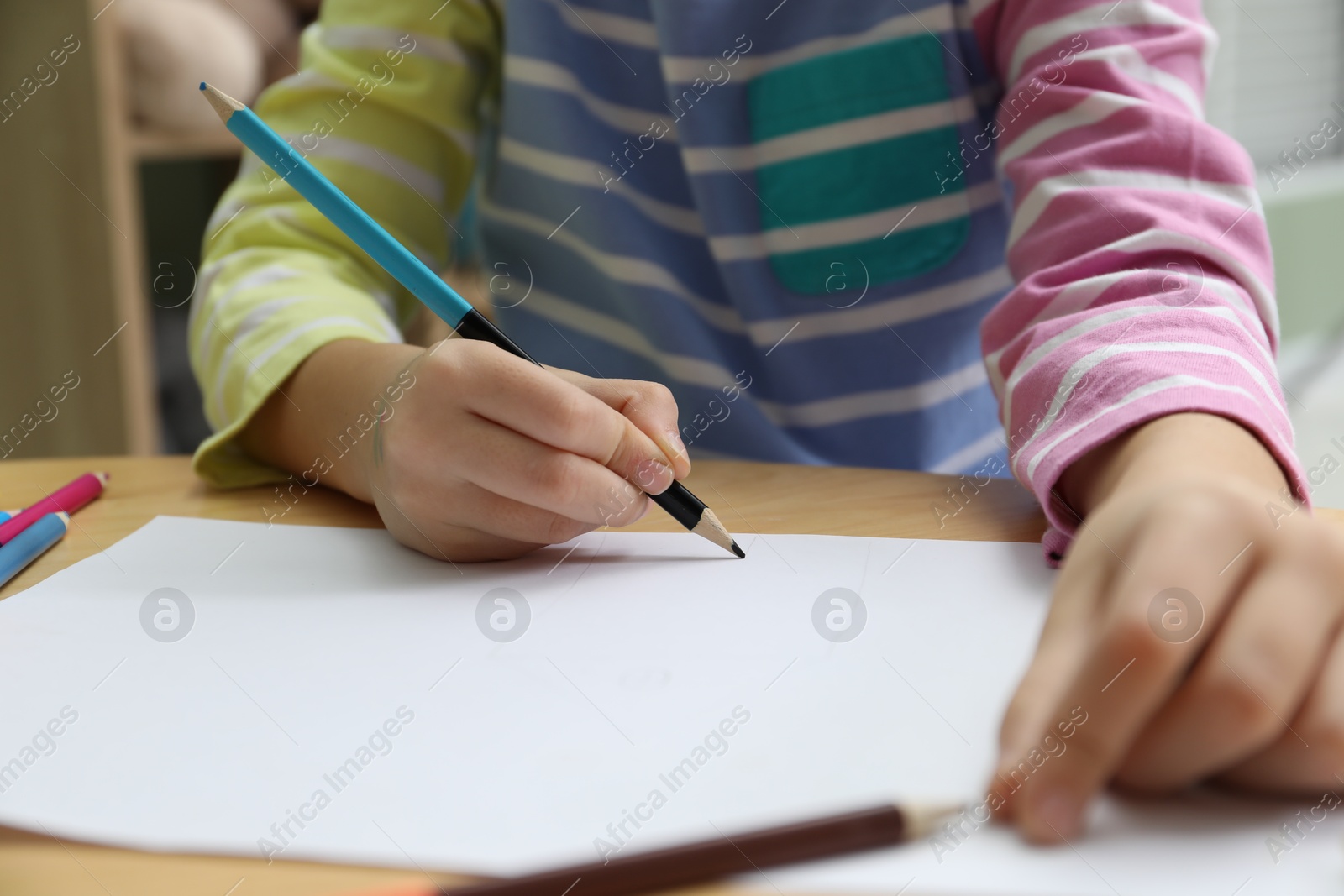 Photo of Child drawing at wooden table in psychologist's office, closeup