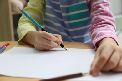 Photo of Child drawing at wooden table in psychologist's office, closeup