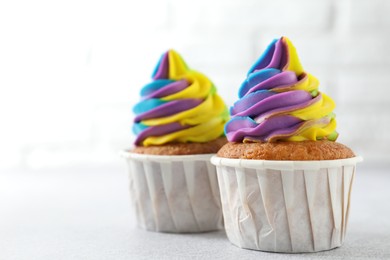 Photo of Tasty cupcakes with colorful cream on white table, closeup. Space for text