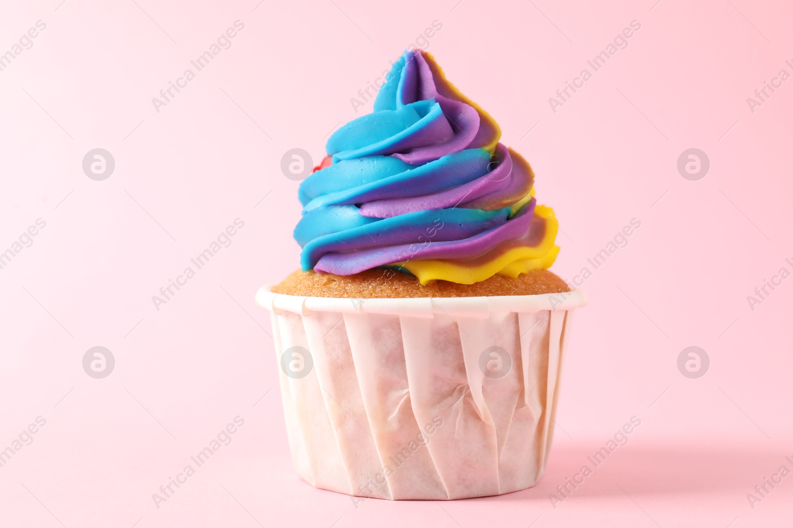 Photo of One delicious cupcake with colorful cream on pink background, closeup