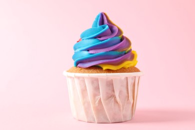 Photo of One delicious cupcake with colorful cream on pink background, closeup