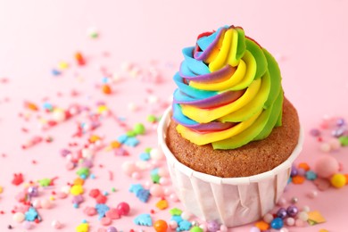 Photo of One delicious cupcake with colorful cream and sprinkles on pink background, closeup. Space for text