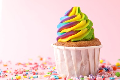 Photo of One delicious cupcake with colorful cream and sprinkles on pink background, closeup. Space for text