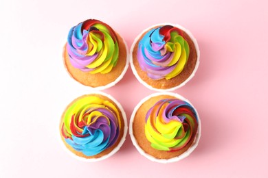 Photo of Delicious cupcakes with colorful cream on pink background, flat lay