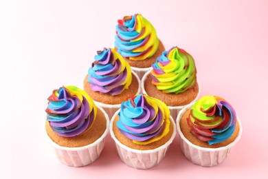 Photo of Delicious cupcakes with colorful cream on pink background, closeup