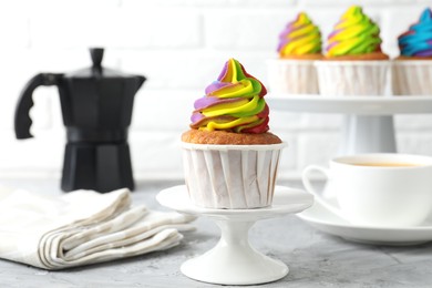 Photo of Delicious cupcake with colorful cream on grey textured table, closeup