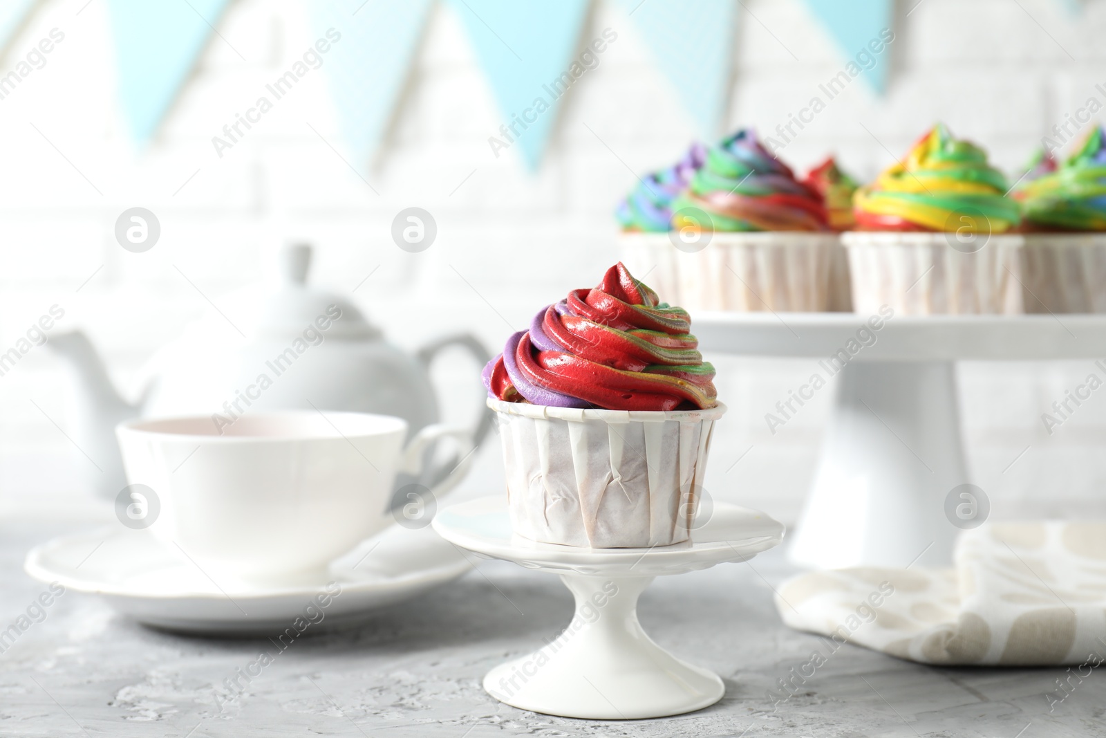 Photo of Delicious cupcake with colorful cream on grey textured table, closeup