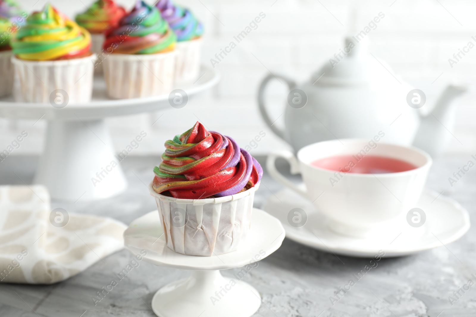 Photo of Delicious cupcake with colorful cream on grey textured table, closeup