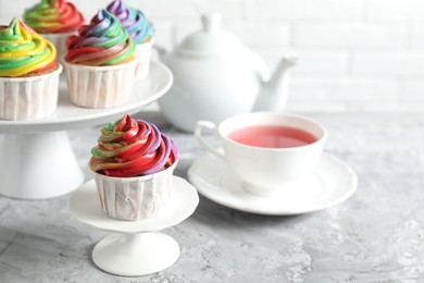 Photo of Delicious cupcake with colorful cream on grey textured table, closeup