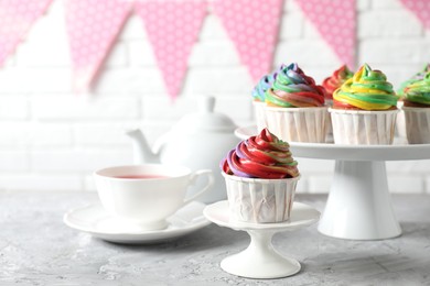 Photo of Delicious cupcake with colorful cream on grey textured table, closeup