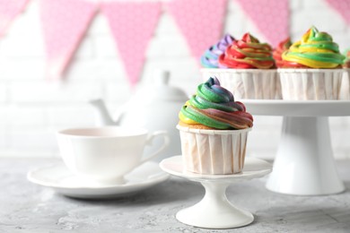 Photo of Delicious cupcake with colorful cream on grey textured table, closeup