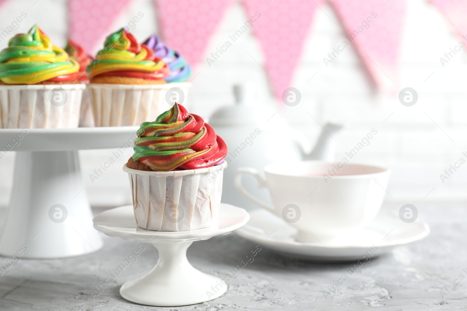 Photo of Delicious cupcake with colorful cream on grey textured table, closeup