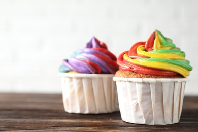 Photo of Delicious cupcakes with colorful cream on wooden table against white background, closeup. Space for text