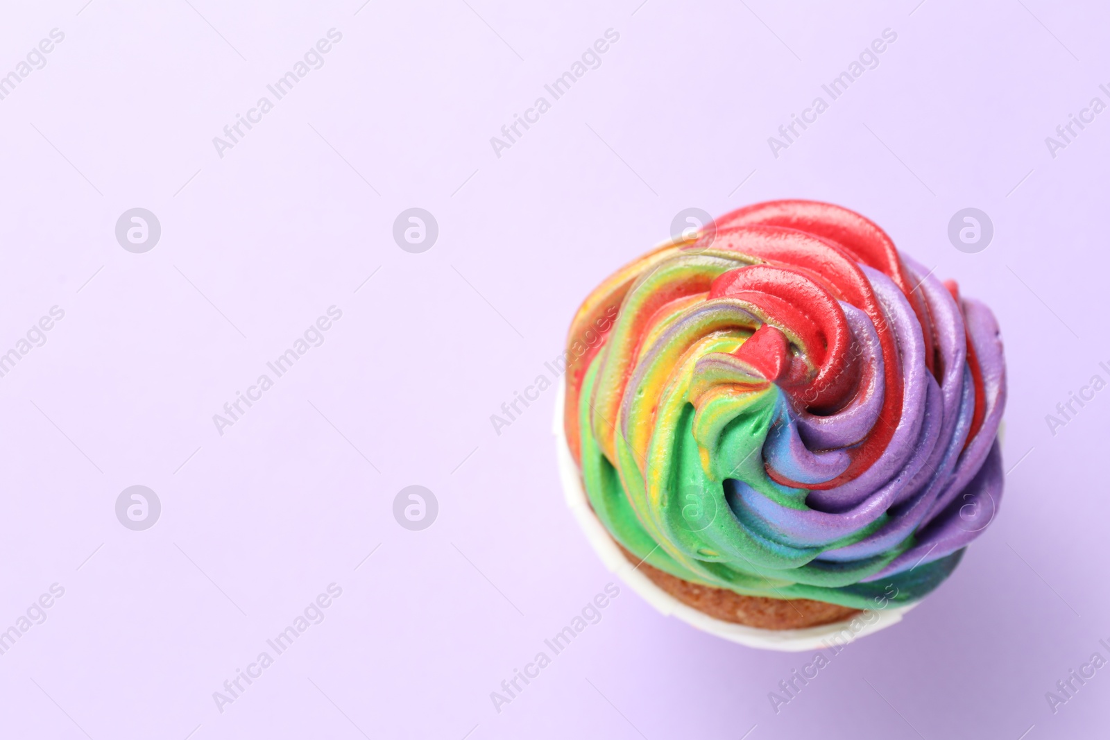 Photo of Delicious cupcake with colorful cream on violet background, top view. Space for text