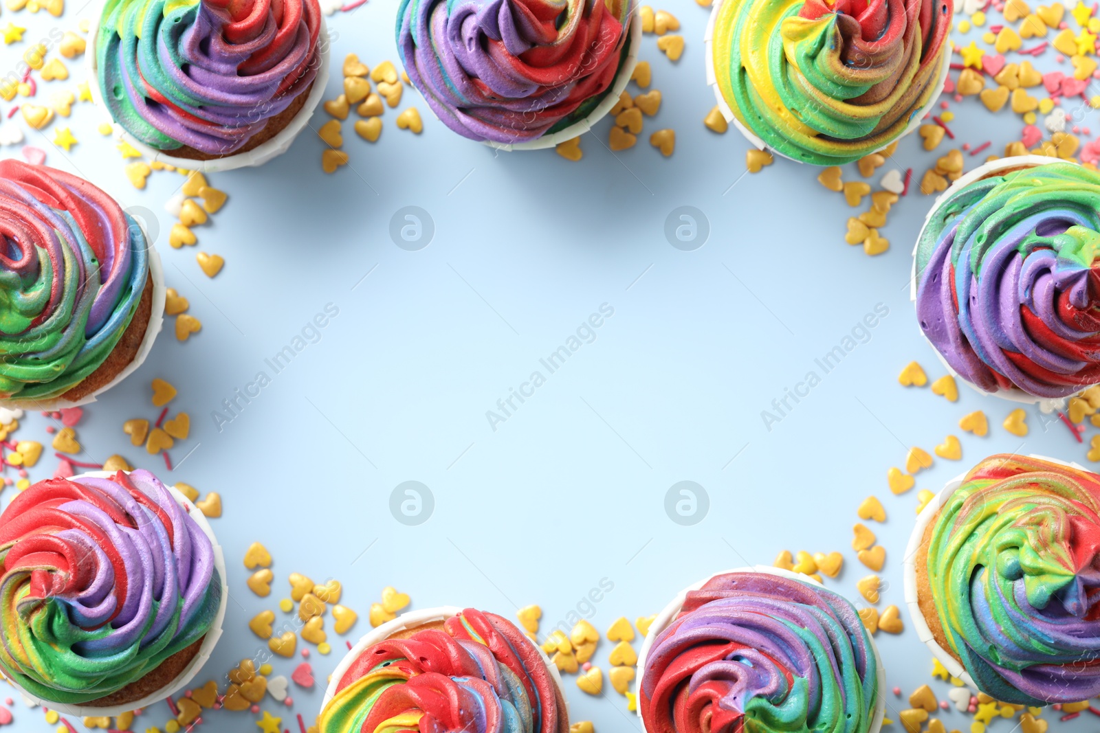 Photo of Frame of delicious cupcakes with colorful cream and confetti on light table, flat lay. Space for text