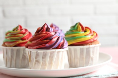 Photo of Delicious cupcakes with colorful cream on pink table, closeup