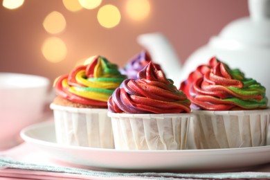 Photo of Delicious cupcakes with colorful cream on table against pink background, closeup. Bokeh effect