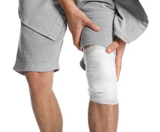 Photo of Man with medical bandage on his knee against white background, closeup