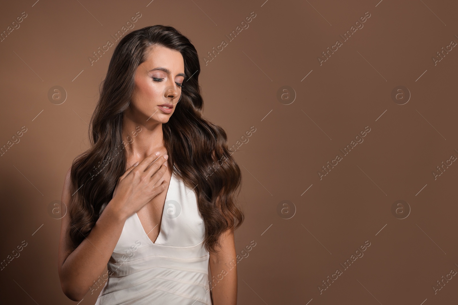 Photo of Hair styling. Beautiful woman with wavy long hair on brown background, space for text