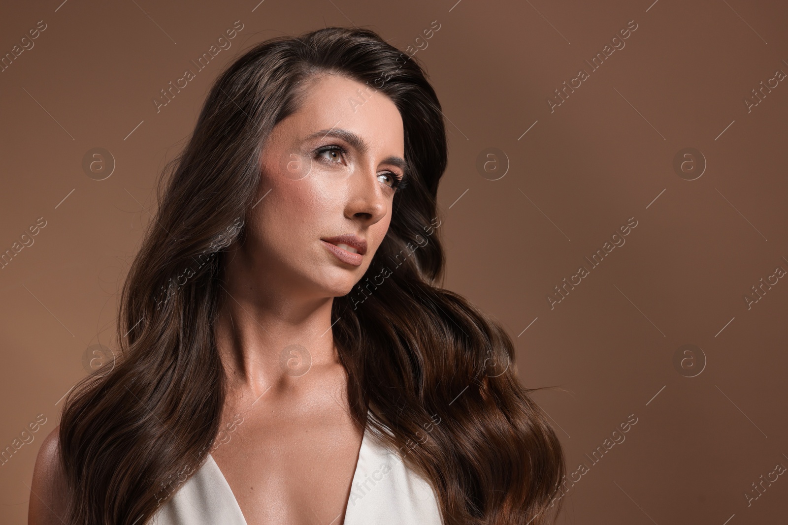 Photo of Hair styling. Beautiful woman with wavy long hair on brown background, space for text