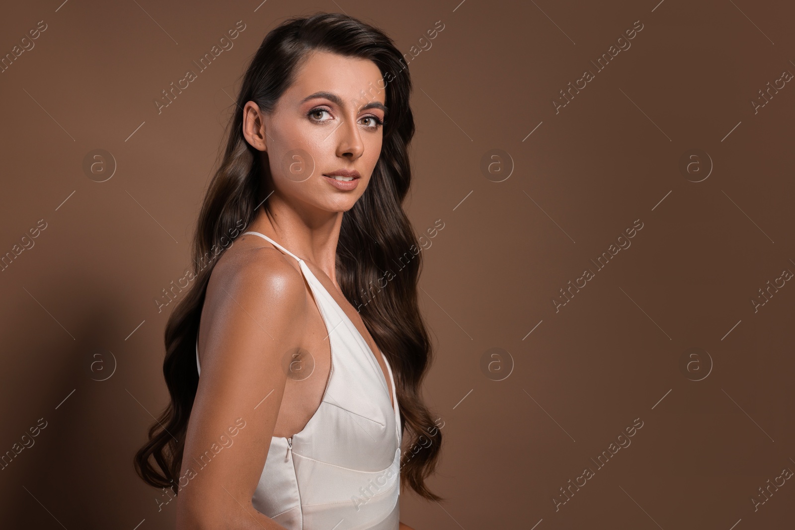 Photo of Hair styling. Portrait of beautiful woman with wavy long hair on brown background, space for text