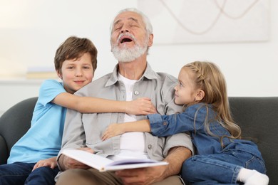 Photo of Grandpa and his grandkids on sofa at home