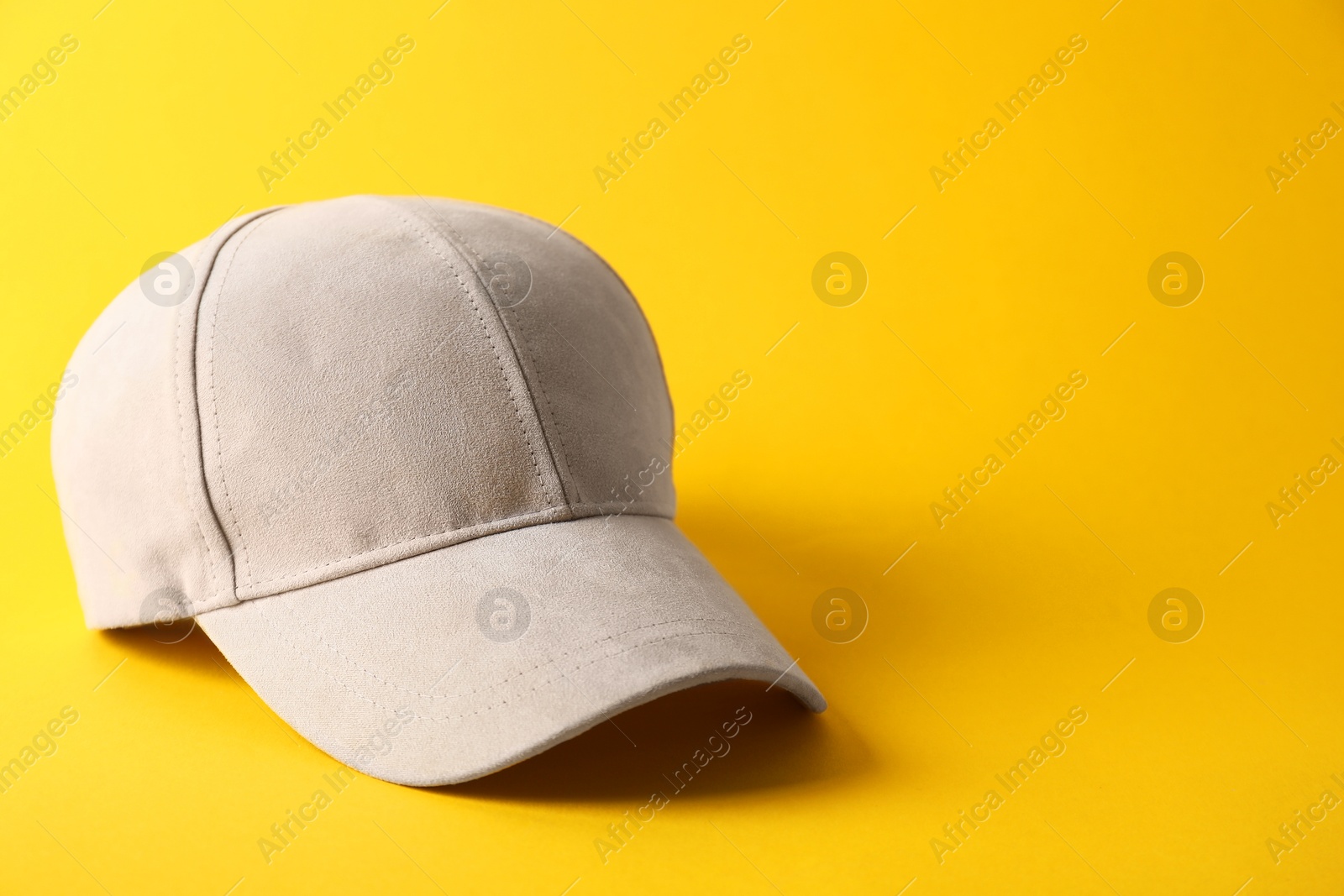 Photo of Stylish baseball cap on yellow background. Mockup for design