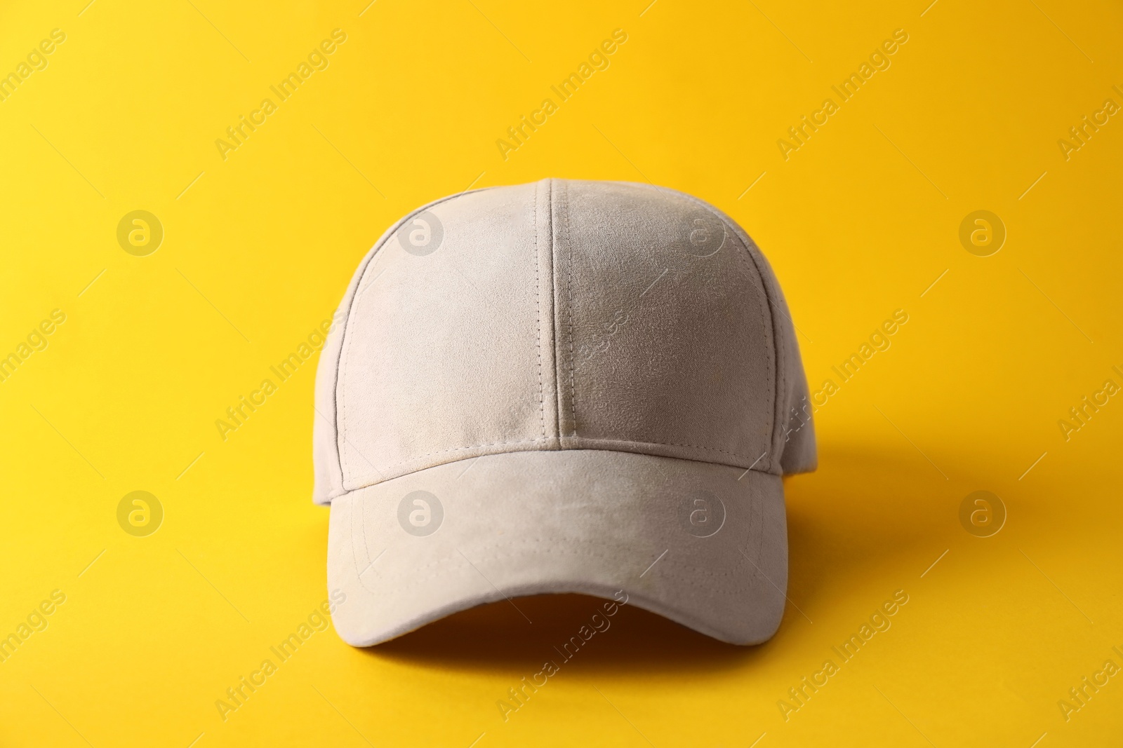 Photo of Stylish baseball cap on yellow background. Mockup for design