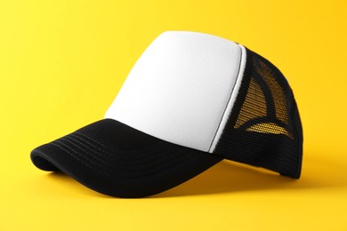 Photo of Stylish baseball cap on yellow background, closeup. Mockup for design