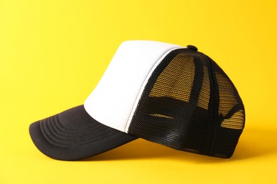 Photo of Stylish baseball cap on yellow background. Mockup for design