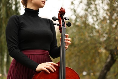 Photo of Young woman with cello outdoors, closeup. Space for text