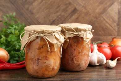 Canned meat in glass jars and other products on wooden table