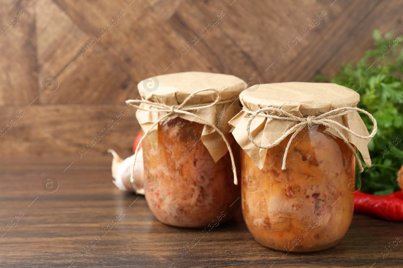 Photo of Canned meat in glass jars on wooden table, space for text